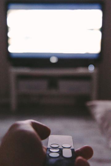 [illustrative] person holding a remote in front of a tv